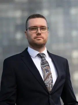 Adwokat Ziemowit Woźniak na tle przeszklonej elewacji w Łodzi