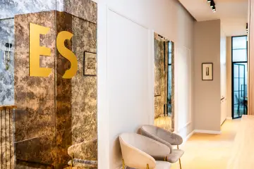 Złote logo E&S na marmurowej ścianie w siedzibie kancelarii w Łodzi